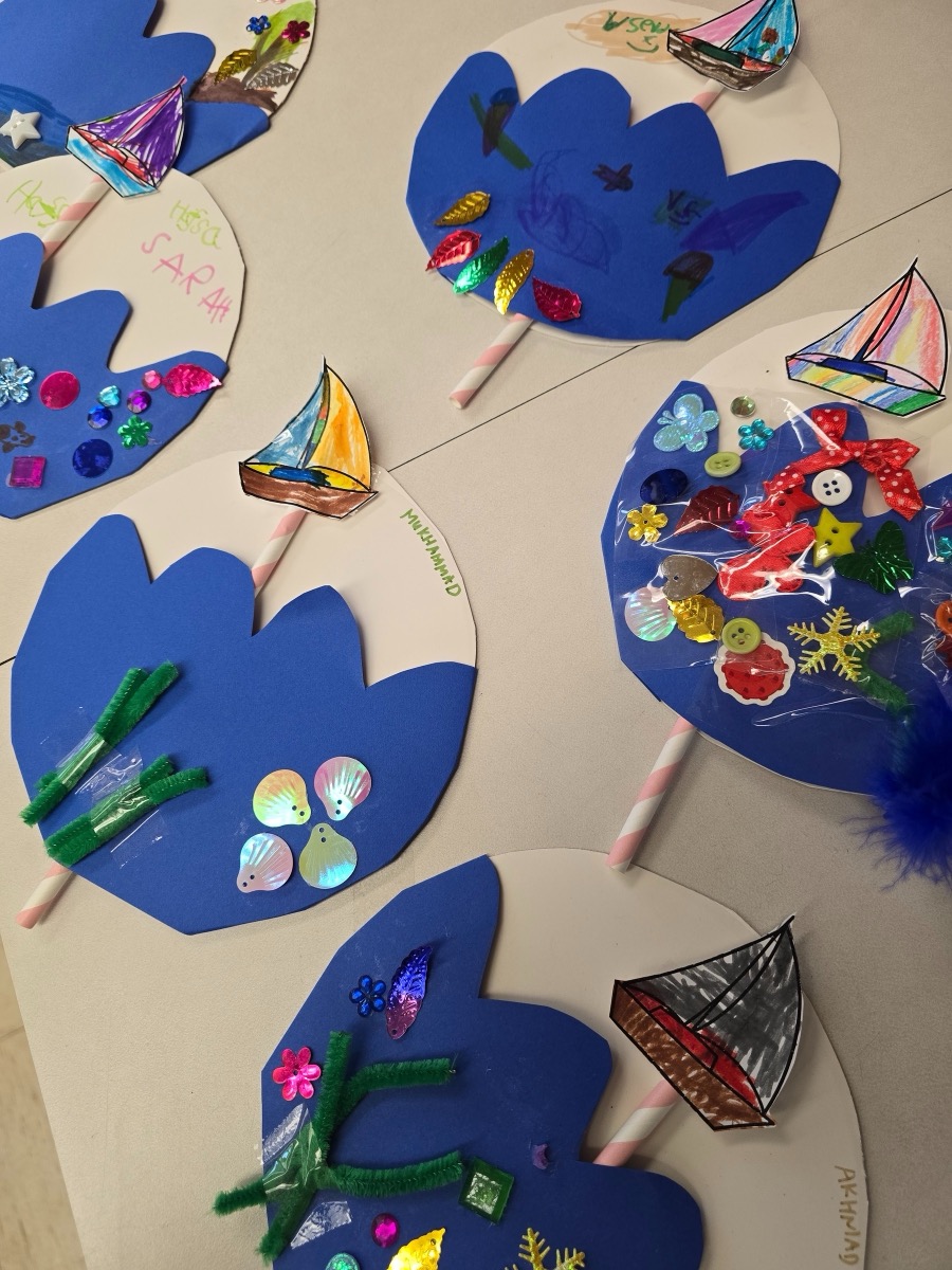 Handmade craft projects with blue paper, sequins and sailboats