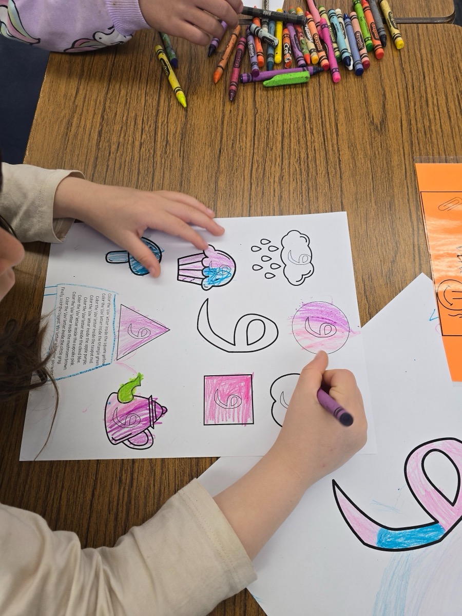 A child coloring Arabic letter worksheets with crayons